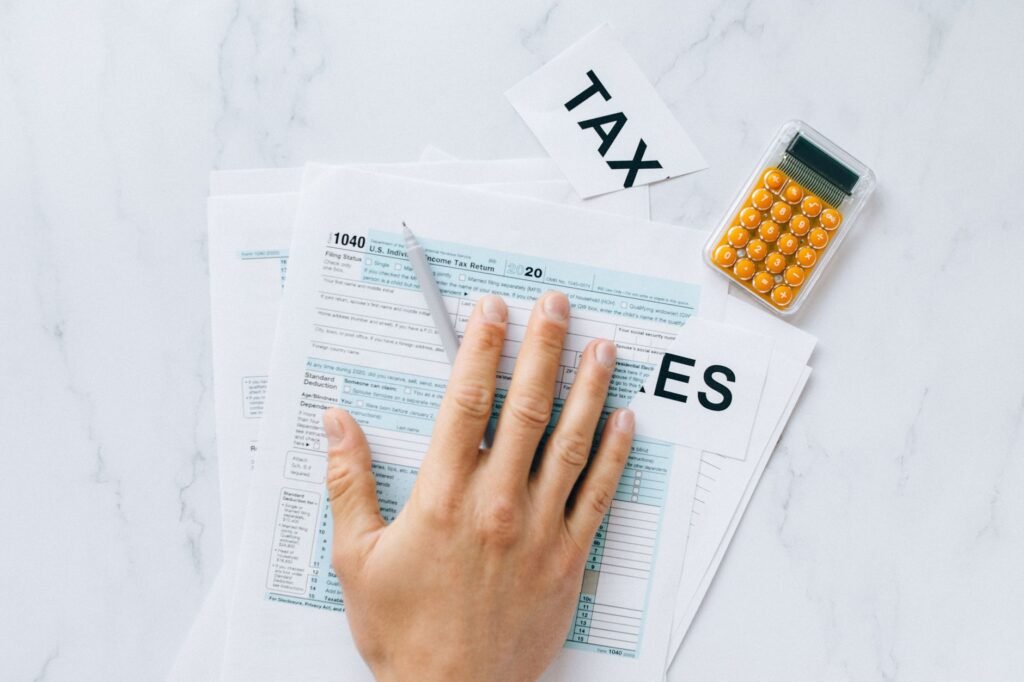 Close-up of a hand on tax form 1040 with a calculator on a desk.