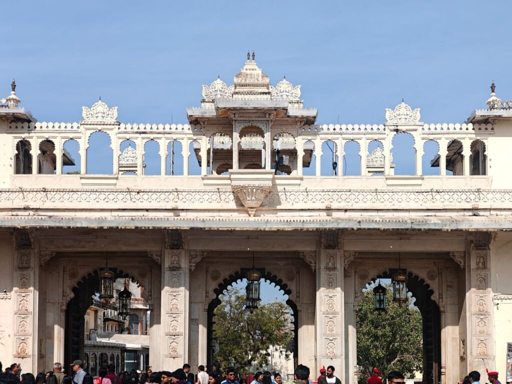 Crowds gather under the ornate gateway of Udaipur City Palace, a historic architectural gem.