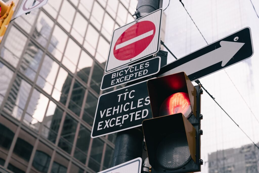 Urban traffic light and signs with building reflection in downtown Toronto.