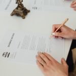 Close-up of hands signing a divorce decree document on a desk, showcasing legal process.