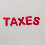 Simple and bold image of the word taxes in red letters on a white background.
