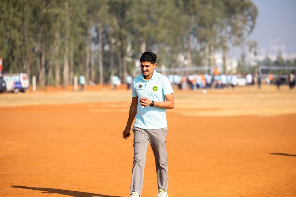Young man in sportswear walking alone on an outdoor dirt field during daytime.