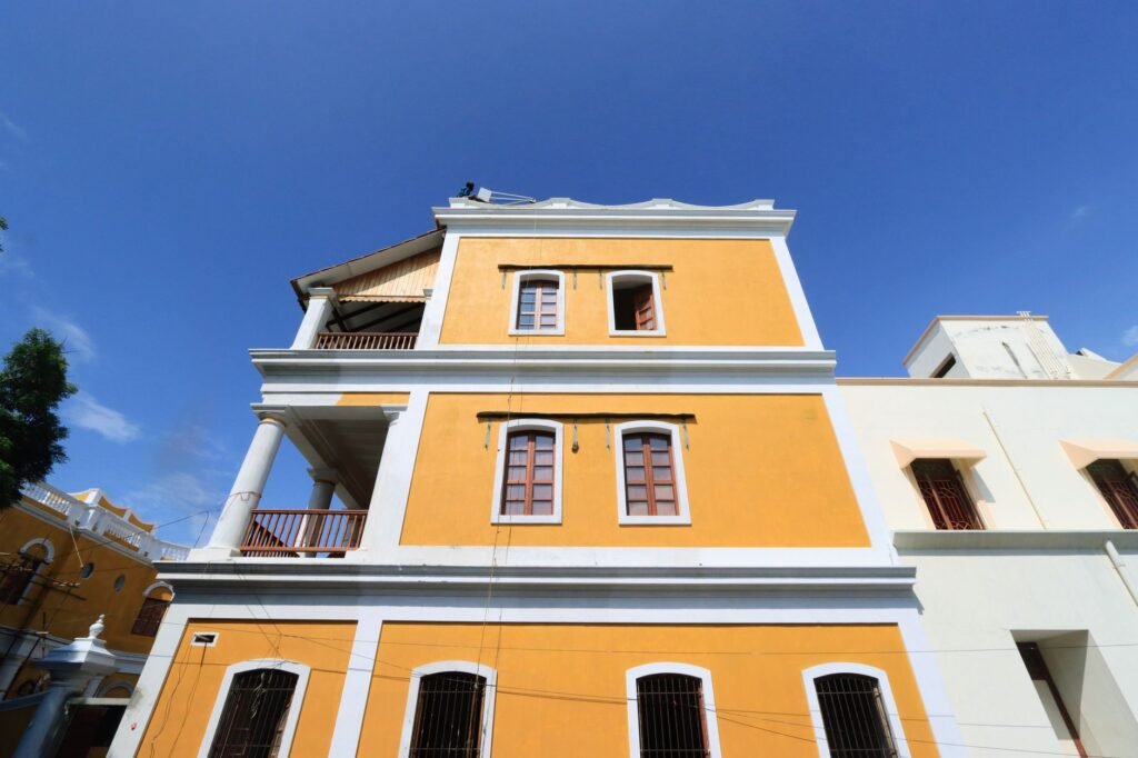 Vibrant yellow colonial building with tall columns under a bright blue sky, showcasing classic architectural style.