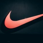 Vibrant red Nike swoosh logo displayed on a dark, minimalist backdrop symbolizing sports and lifestyle.
