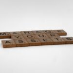 Wooden Scrabble tiles spelling 'Manage Your Assets' on a white background.