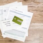 Top view of credit card and application documents on wooden surface.