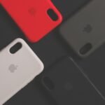 Four colorful smartphone cases on a dark surface, showcasing variety and design.