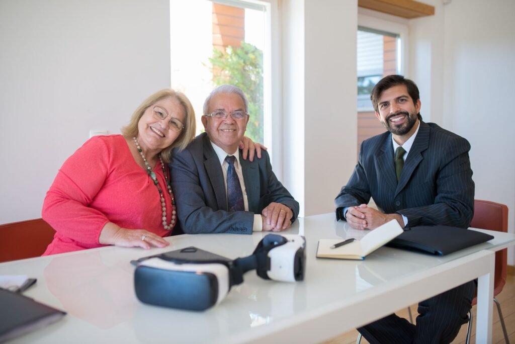 Elderly couple smiling with real estate agent during home meeting, showcasing modern technology.
