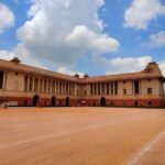 Wide view of Rashtrapati Bhavan in Delhi, India on a sunny day with blue skies and white clouds.