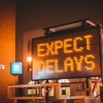Mobile electronic traffic sign with inscription Expect delays placed on road in city street in evening time