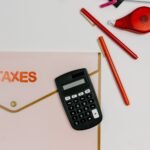 Flat lay image featuring a calculator, pens, and a folder labeled 'TAXES', perfect for finance-related themes.