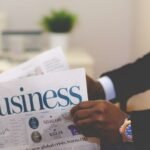 Close-up of a businessman reading a newspaper indoors, focusing on business headlines.