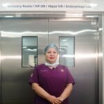 A healthcare professional standing in a hospital corridor in front of the recovery room and IVF lab.