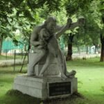 Sculpture of Eklavya and Dronacharya, Raipur, India, amidst lush greenery.
