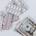 Top view of different blisters of medications and pills composed with heap of paper money