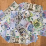 A collection of US dollars, euros, and Turkish lira banknotes on a wooden surface.