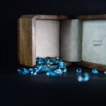Wooden jewelry box displaying scattered blue gems, symbolizing elegance and luxury.