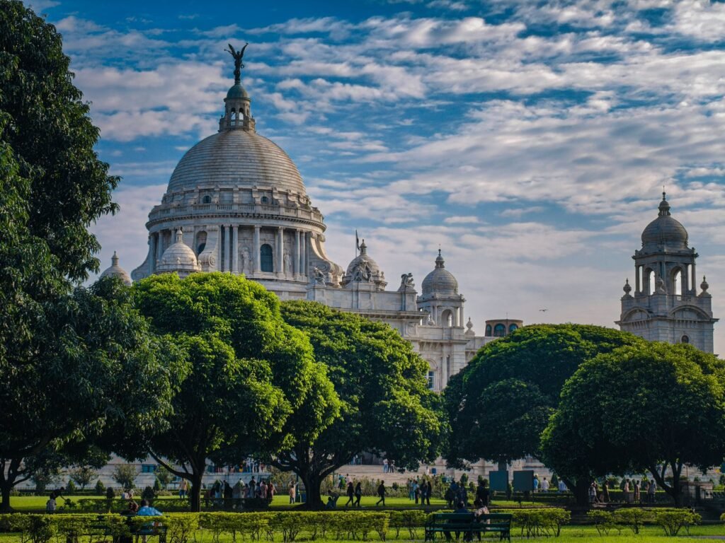 View of the iconic Victoria Memorial in Kolkata surrounded by lush greenery on a sunny day.