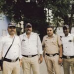 Four policemen in uniform standing on a street in Mumbai, India.