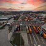 Aerial view of a bustling shipping yard with colorful containers at sunset, highlighting logistics.