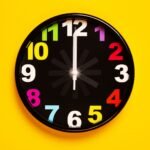Vibrant wall clock with colorful numbers on a bright yellow background, emphasizing modern decor.
