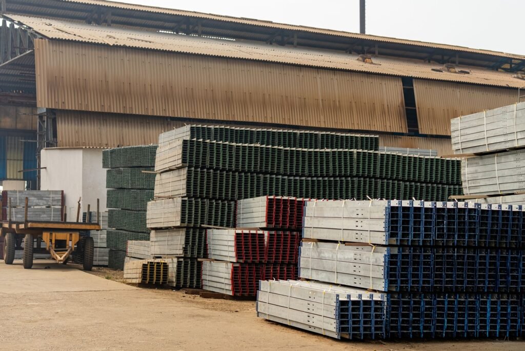 Outdoor view of an industrial warehouse with multiple stacks of metal beams and pallets.
