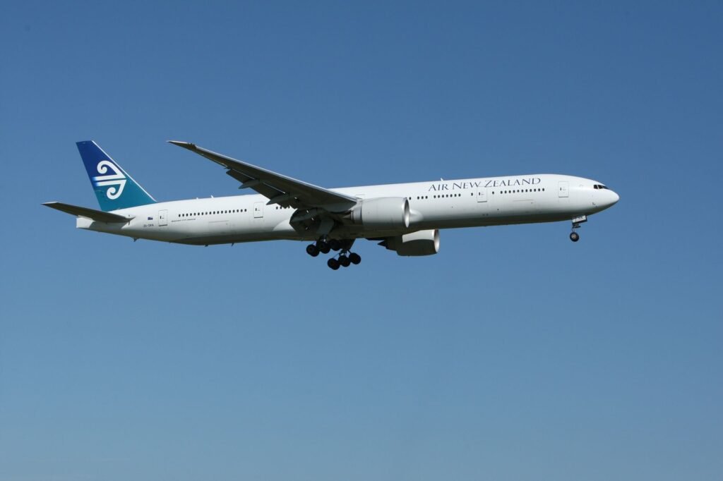 Air New Zealand Boeing 777 airliner flying against a clear blue sky, showcasing aviation travel.