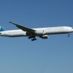 Air New Zealand Boeing 777 airliner flying against a clear blue sky, showcasing aviation travel.