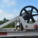 Close-up of a metal gear mechanism used for lifting 10 tons outdoors on a sunny day.