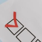 Close-up of a red check mark on a crisp white paper with black boxes, symbolizing completion.