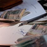 Overhead view of Polish banknotes, documents, and a pen on a desk, highlighting financial planning.