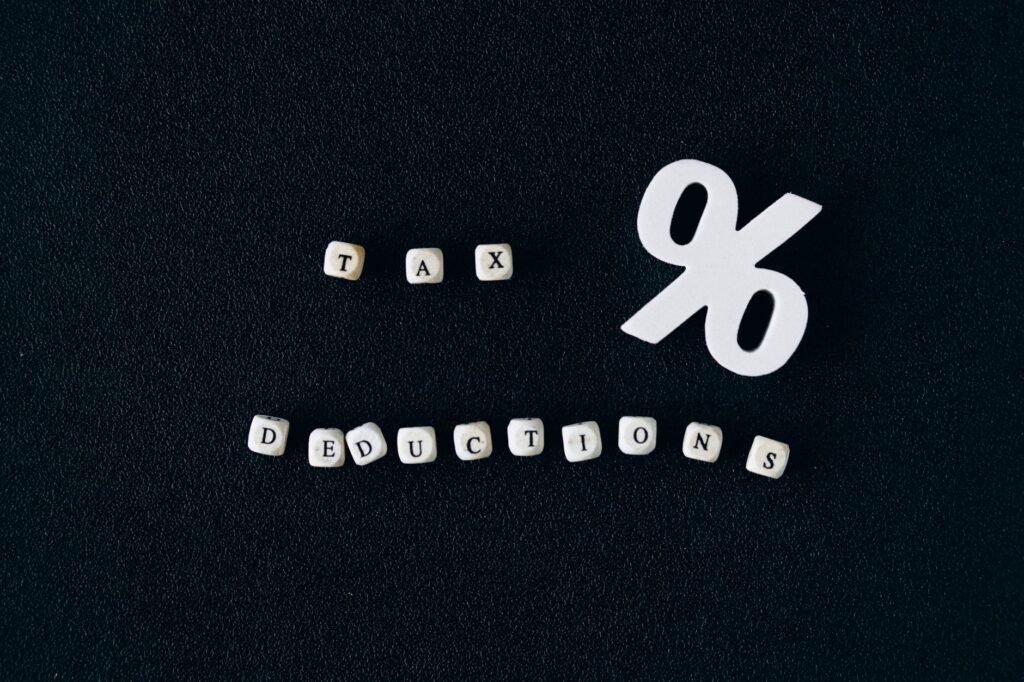 Conceptual image of tax deductions with alphabet blocks and percent symbol on black surface.