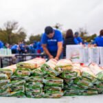 Volunteers distributing packaged food in an outdoor charity event.