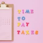 Colorful tax reminder on clipboard against a pink background for March