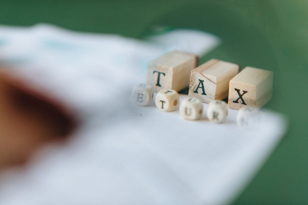 Wooden blocks and dice spelling 'Tax Return' on a blurred green background.