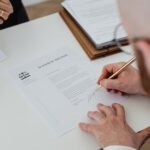 Close-up of a person signing a divorce decree on a desk.