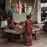 Authentic Indian market stall with women in traditional attire interacting. Vibrant cultural snapshot.