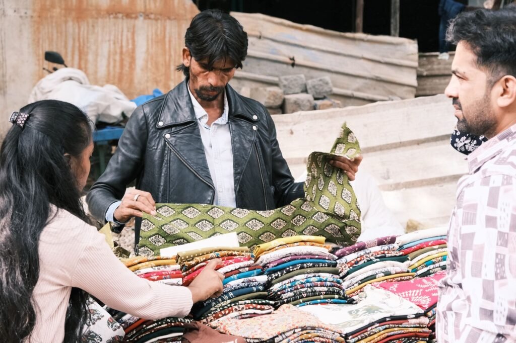 People browsing colorful fabrics at a Bengaluru street market.