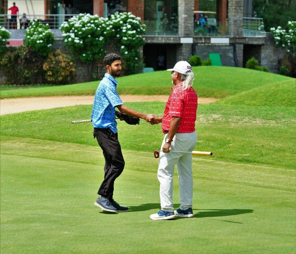 Two golfers shake hands on a lush green course in Hyderabad, India, celebrating their game.