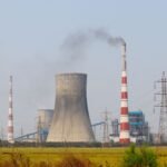 Aerial view of an industrial power plant in Vijayawada, India, with cooling towers and chimneys emitting smoke.