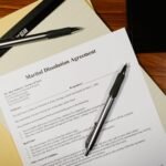 Flat lay of a marital dissolution agreement form with pens and files on a desk.