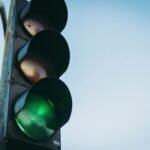Close-up of a green traffic light against a clear blue sky, symbolizing go and safety.