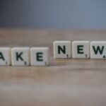 Scrabble tiles spelling 'Fake News' on a wooden surface highlighting misinformation.