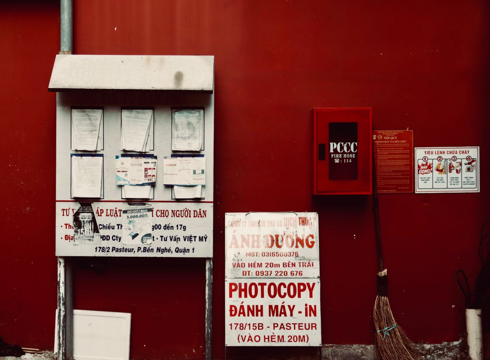 City environment with notices and fire hose on a vibrant red wall.