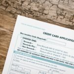 Top view of a credit card application form on rustic wooden background.