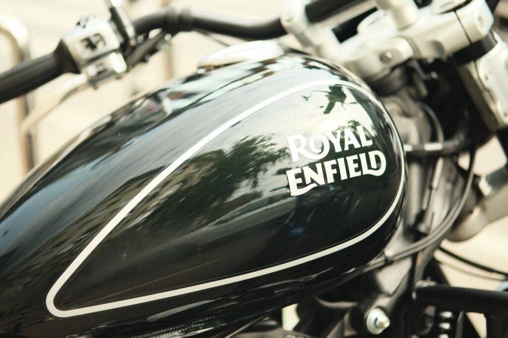 Detailed close-up of a Royal Enfield motorcycle tank showing its shiny design and logo.