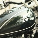 Detailed close-up of a Royal Enfield motorcycle tank showing its shiny design and logo.