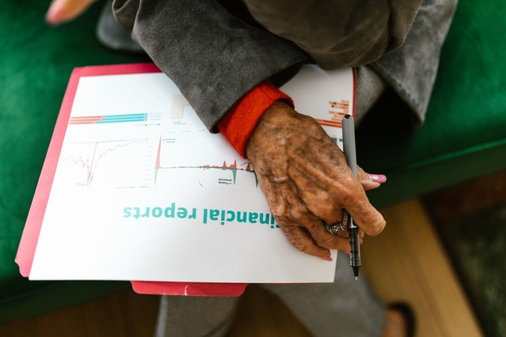Close-up of an elderly woman holding a pen with a financial report.