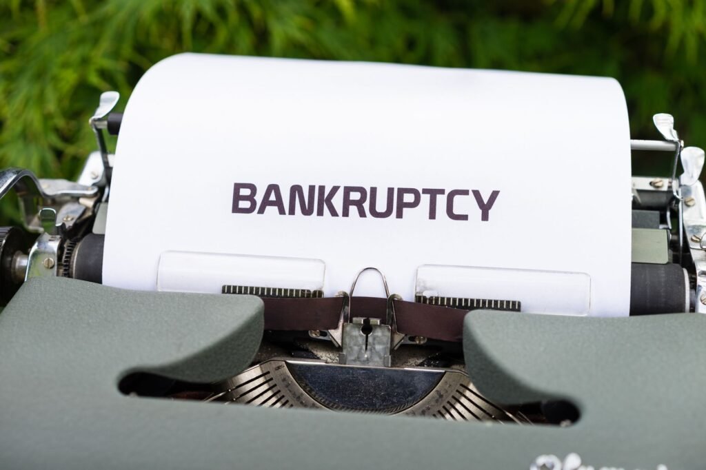 Close-up of a typewriter with the word 'BANKRUPTCY' on paper, surrounded by greenery.