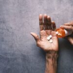 Elderly person's hand pouring pills from a bottle, offering ample copy space.